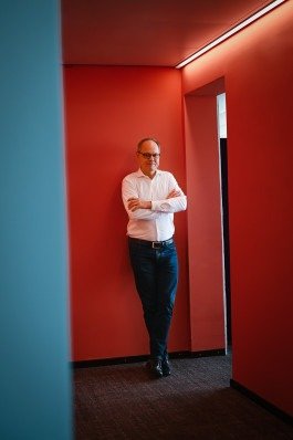 Kai Gniffke portraitiert für Journalist Magazin mit roten Hintergrund im Büro. 