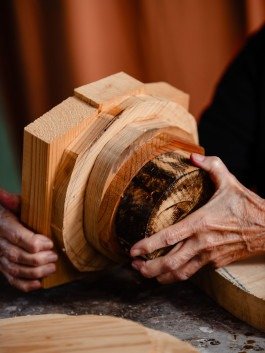 Reportage Fotografie Beispiel, Hände einer Künstlerin, die eine kleine Holzskulptur hält. 