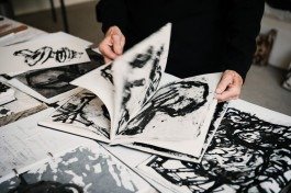 Eine Künstlerin blättert in ihrem Skizzenbuch. 