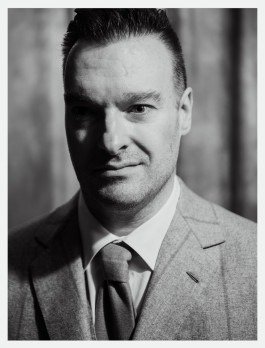 Schwarz-weißes Künstlerportrait eines Musikers in klassischen Anzug, Schatten auf seinem Gesicht. 